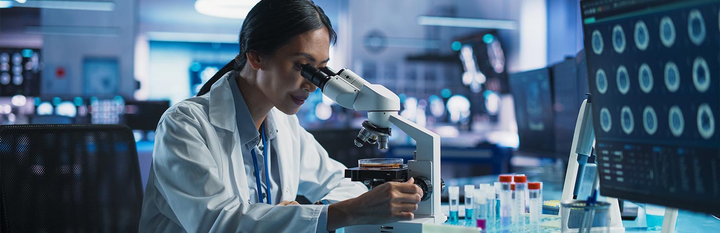 medical researcher in a lab looking through a microscope